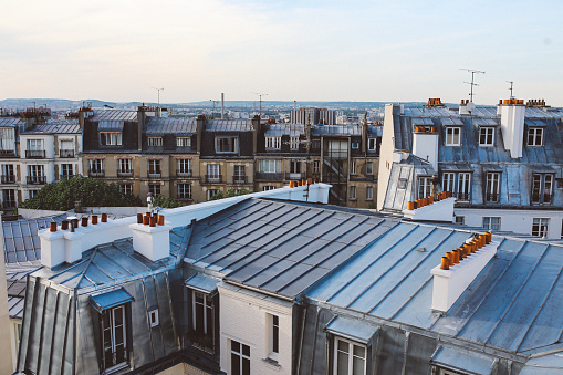 Vintage toned image of a traditional Parisian old residential building and the beautiful rooftops in Montmartre on a bright and sunny day, under the clear blue skies. Film emulation color grading added for more vintage feel.