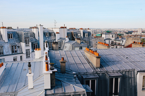 Vintage toned image of a traditional Parisian old residential building and the beautiful rooftops in Montmartre on a bright and sunny day, under the clear blue skies. Film emulation color grading added for more vintage feel.