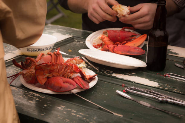 istock Hands cracking lobsters on a wooden picnic table 537474316