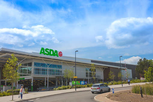 Telford, United Kingdom - May 31, 2016: An editorial stock photo of the ASDA supermarket in Telford, Shropshire in the United Kingdom. People can be seen walking towards the parking area after shopping. Asda is an American-owned, British-founded supermarket retailer. The company became a subsidiary of the American retail corporate giant Walmart after a £6.7 billion takeover in July 1999, and was the second-largest supermarket chain in Britain between 2003 and 2014, by market share.