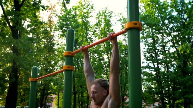 Sports lifestyle, street workout. Muscular man performs an exercise power outlet. Outdoor sports ground