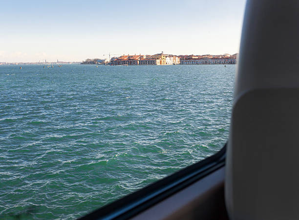 View of Venice lagoon from inside the train carriage traveling on tracks on the water.