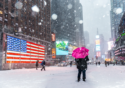 Time Square in snow storm with unrecognizable people on the background