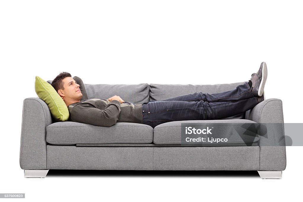 Pensive young guy laying on a sofa Pensive young guy laying on a sofa isolated on white background Sofa Stock Photo
