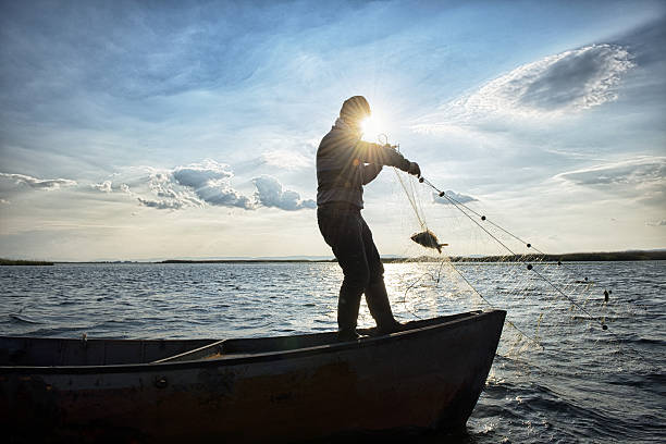 alter fischer auf seinem boot - fishing net stock-fotos und bilder