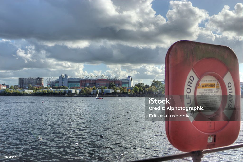 Old Trafford Football stadium Manchester, United Kingdom - October 4, 2014: Dark clouds over Manchester United football stadium, Old Trafford. In the foreground is a lifebuoy. Old Trafford Stock Photo