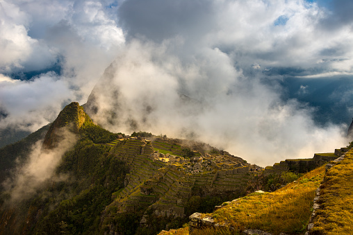 Machu Picchu illuminated by the first sunlight coming out from the opening clouds. The Inca's city is the most visited travel destination in Peru.
