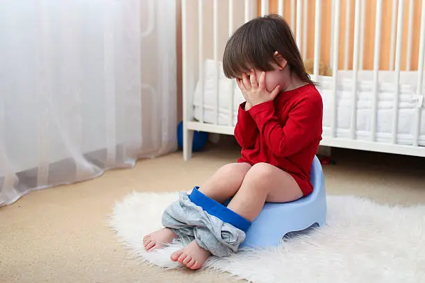 crying little child sitting on potty at home