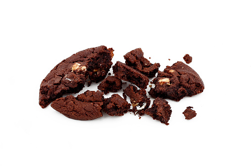 A dark chocolate cookie with white chocolate chips broken in pieces with crumbs on isolated background.