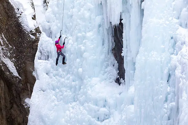 A woman climbs a frozen waterfall.