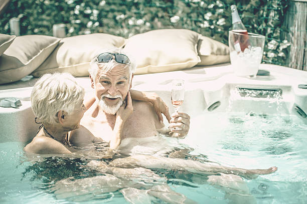 radosny starsza para picia wina w jacuzzi - couple hot tub spa treatment health spa zdjęcia i obrazy z banku zdjęć