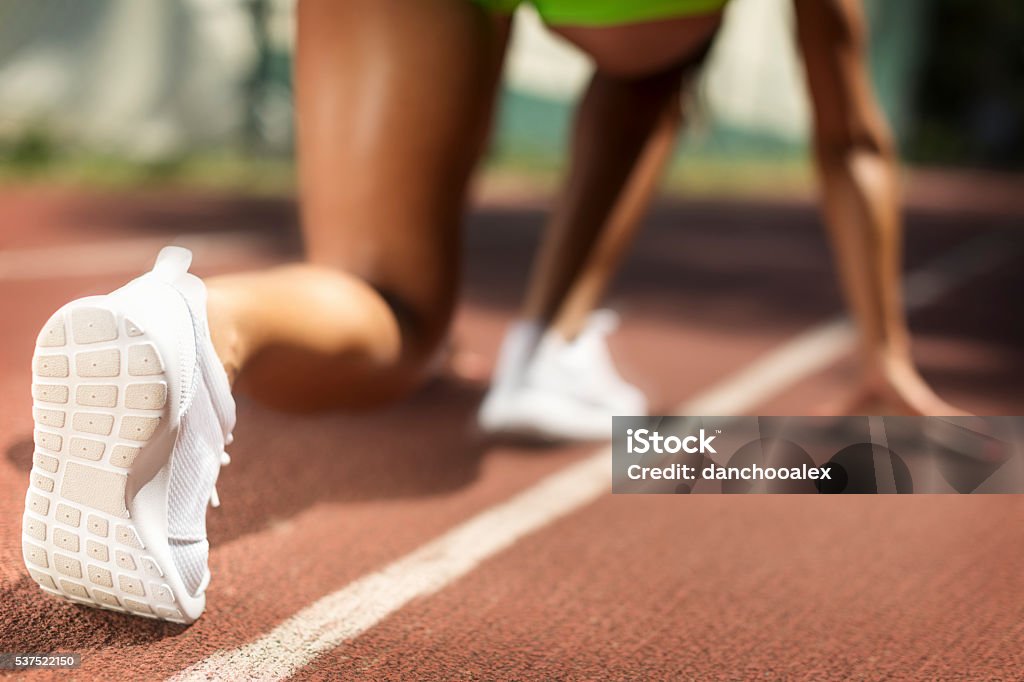 Racer at starting point close up shot Female athlete streching and running. Shallow DOF. Developed from RAW; retouched with special care and attention; Small amount of grain added for best final impression. Adobe RGB color profile. Beginnings Stock Photo