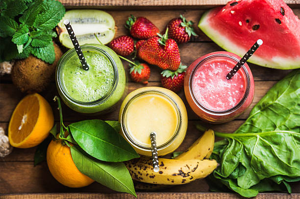 Freshly blended fruit smoothies of various colors and tastes Freshly blended fruit smoothies of various colors and tastes in glass jars in rustic wooden tray. Yellow, red, green. Top view, selective focus foxys_forest_manufacture stock pictures, royalty-free photos & images
