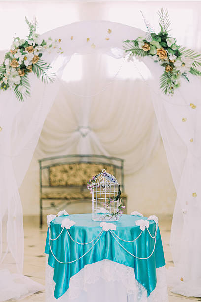 istock Beautiful decorative birdcage on fancy decorated table under wedding arch 537523120