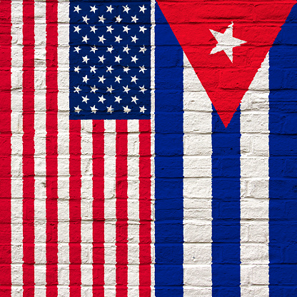 Flags of the USA and Cuba painted onto a white brick wall