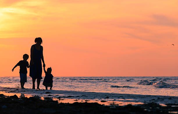 istock mother and two kids walking at sunset beach 537527812