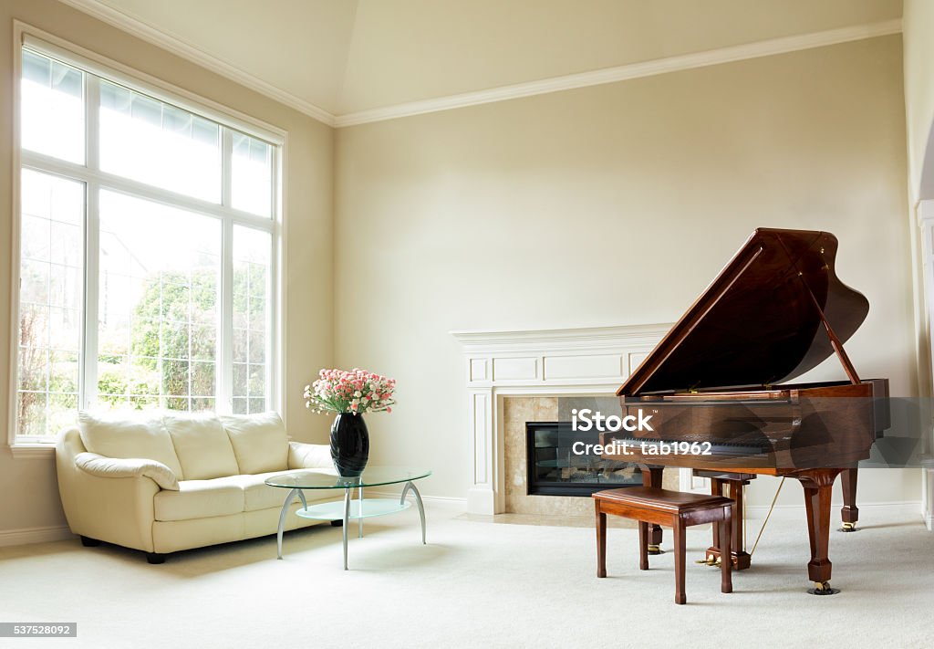 Bright daylight living room with grand piano Living room with grand piano, fireplace, sofa and large window with bright daylight coming through. Piano Stock Photo