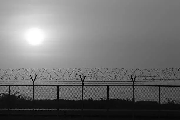 silhouette security with a barbed wire fence at sunset time, back and white photo