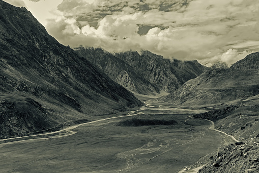Aerial view of moody and rocky landscape of Kargil, with mountain peaks and cloudy sky  in background , green valley , Leh, Ladakh, Jammu and Kashmir, India