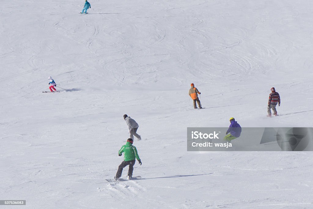 Skiers and snowboarders going down the slope. Skiers and snowboarders going down the slope at ski resort. 2015 Stock Photo