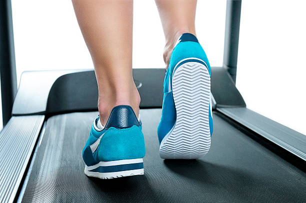 istock Female legs in turquoise sneakers on a treadmill. 537536519