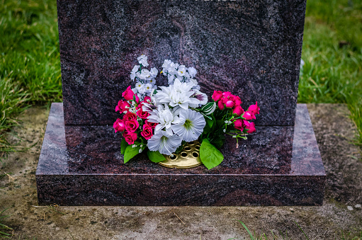 flowers on a black granit headstone, cemetery, colour image