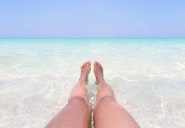 istock Sun tanned legs in clear water on paradise beach. 537537618