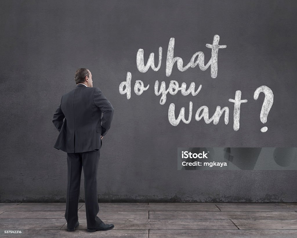 Businessman with “what do you want?” Text on the Wall Rear view of businessman standing on wooden floor and looking at the “what do you want?” text written with chalk on the wall. Adult Stock Photo Businessman with “what do you want?” Text on the Wall Rear view of businessman standing on wooden floor and looking at the “what do you want?” text written with chalk on the wall. Adult Stock Photo