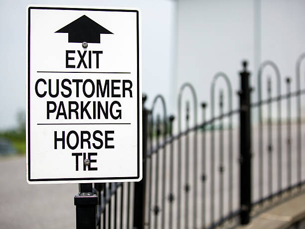A white sign with a black border with the words EXIT, Customer Parking and Horse tie.