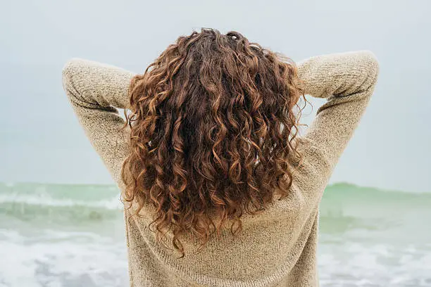 Photo of Curly brunette in a sweater on the coast