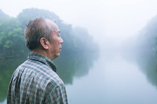 istock old man standing infront of lake in the mist 537544240