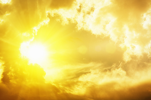 The sun, shining through a gap in dark clouds, creates radiated lens flare. The entire image could be used as a background.