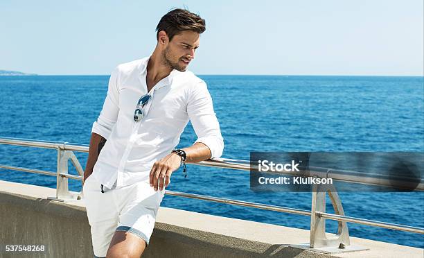 Hombre Guapo Posando En Ropa Blanca Usando Un Escenario Al Mar Foto de stock y más banco de imágenes de Hombres