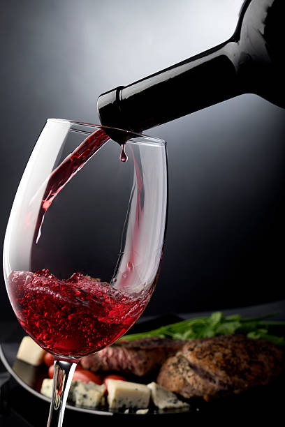 acercamiento de verter el vino tinto en vidrio - pink pepper fotos fotografías e imágenes de stock