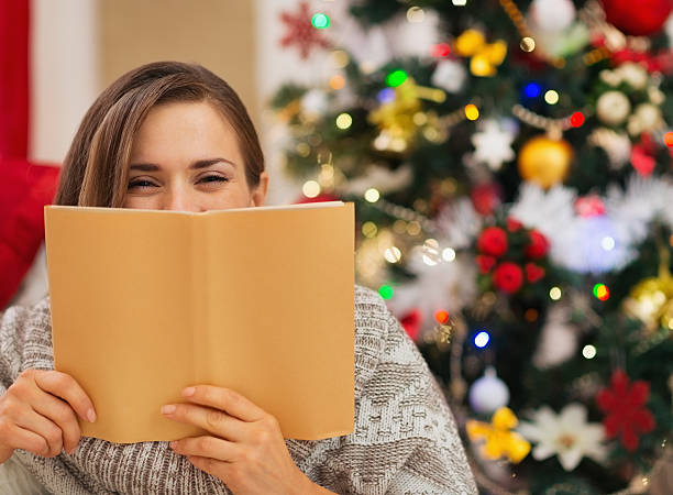 istock woman hiding behind book in front of christmas tree 537549320