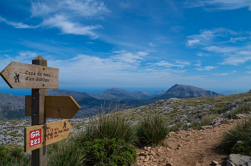 wooden signpost in Mallorca along the GR 221 guiding the hikers, with beautiful view over the serra de tramuntana