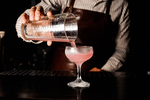 istock barman preparing and pouring cosmopolitan alcoholic pink cocktail at bar. 537551254