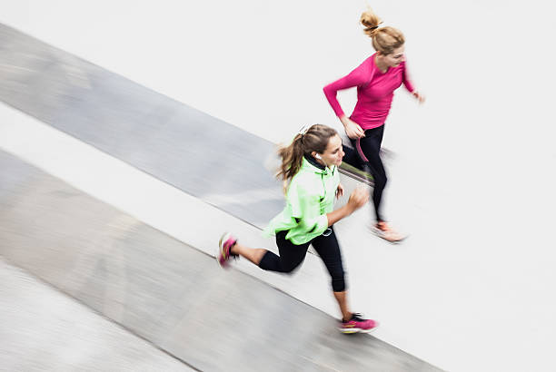 Blurred motion photo of two sportsmen running on scenic road.