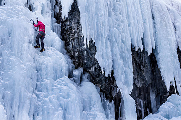 A woman climbs a frozen waterfall.