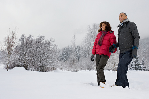A mature couple walking through snow