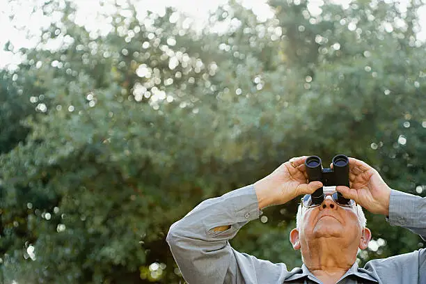 Photo of Senior man looking through binoculars