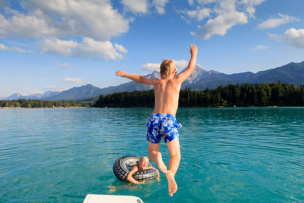 niño y niña en la natación faakersee en carintia - child jumping swimming nautical vessel fotografías e imágenes de stock