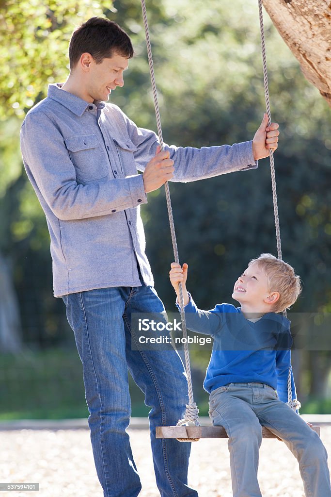 family at swings loving family of two having fun swinging in the park 2015 Stock Photo