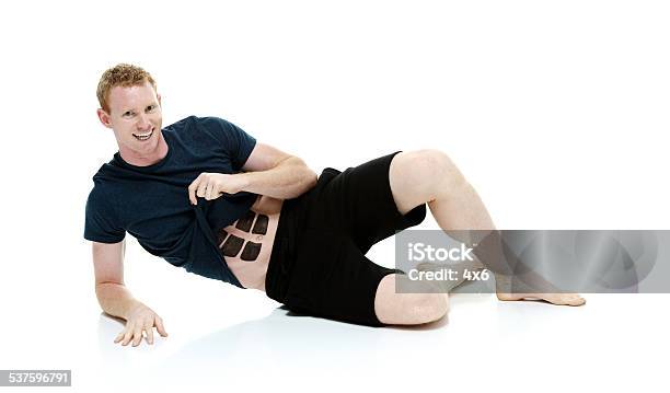 Cheerful Man Lying On Ground With Fake Six Pack Stock Photo - Download Image Now - 20-29 Years, 2015, 25-29 Years