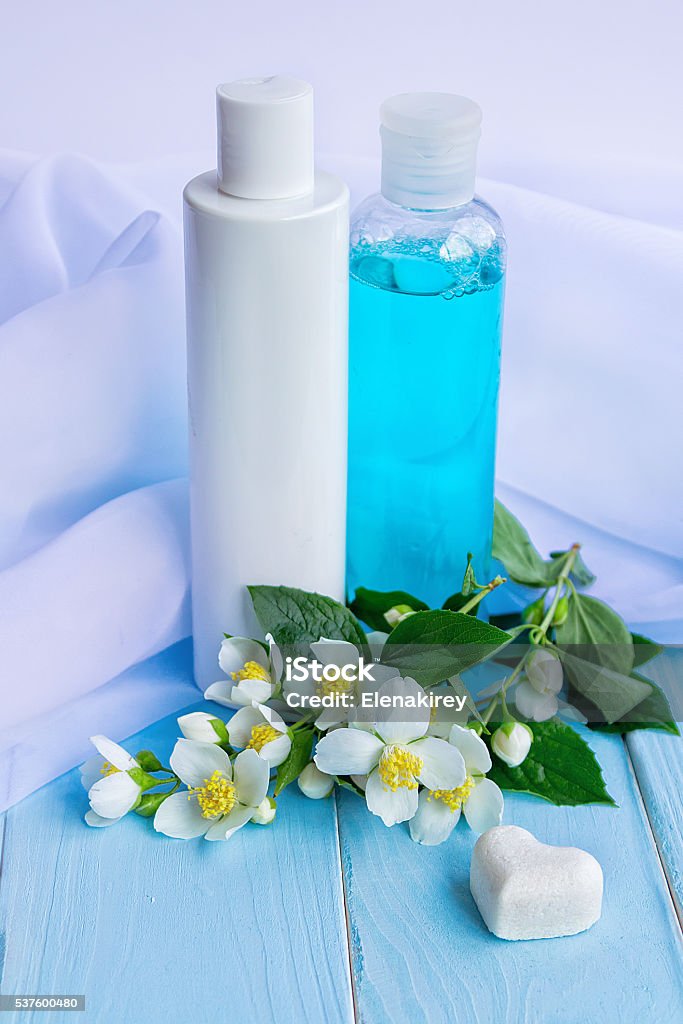 Jasmine essence perfumed products Lotion and tonic in bottles, flowers, white cloths, heart shaped soap and beads - using jasmine essence for cosmetic products concept Backgrounds Stock Photo