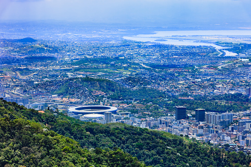 Looking at a section of the large South American City of Rio de Janeiro from the Corcovado peak. To the left of the image, the circular structure, is the well known Maracanã Stadium.; and in front of it the Maracanãzinho, or little Maracanã. In the far distance is the Atlantic Ocean.  Photo shot in the morning sunlight; horizontal format. Copy space.