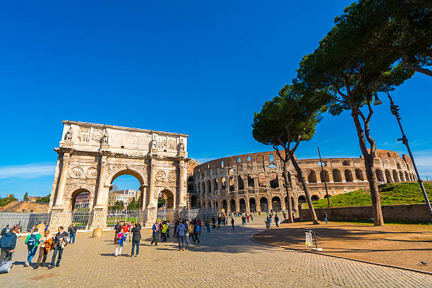 Rome, Italy - February 24, 2016: The Arch of Constantine and the Roman Colosseum in Rome, Italy. Tourists can be seen walking around, exploring the area.