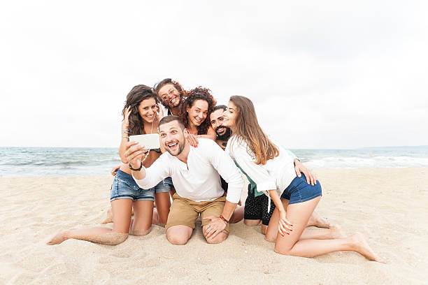 istock Group of friends kneeling on sand and making selfe 537606134