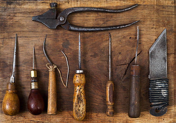 Leather craft tools on a wooden background. Craftmans work desk. Piece of hide and working handmade tools on a work table. Top view.