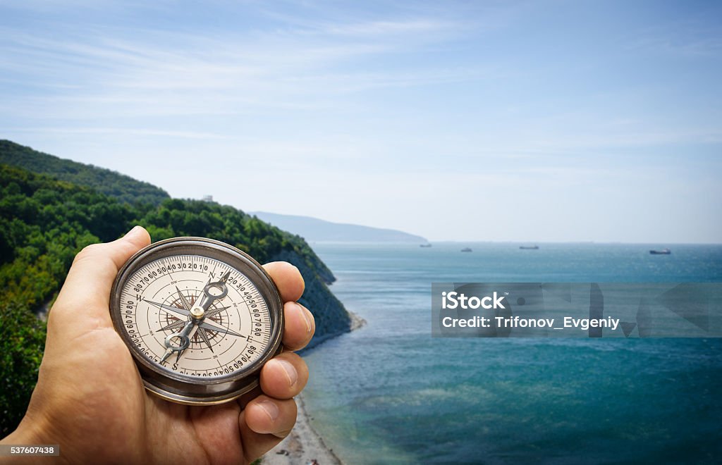Compass Compass in the hand on the nature background. Globe - Navigational Equipment Stock Photo